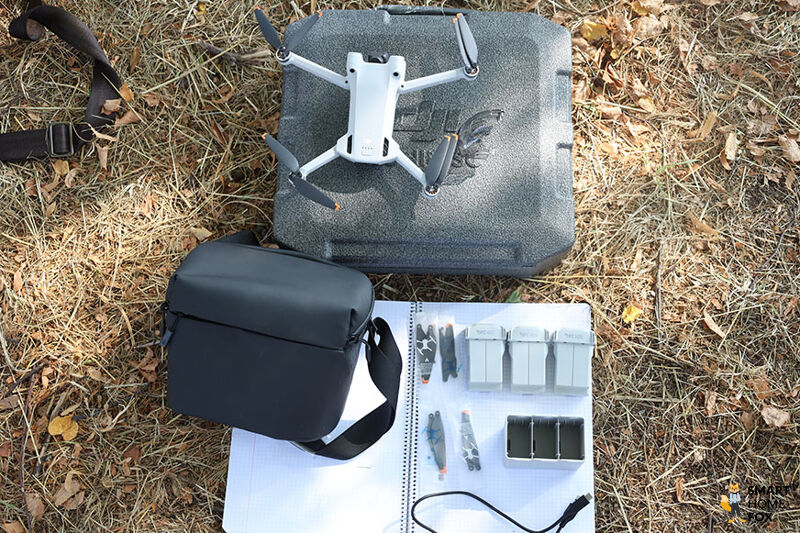 Das Zubehör des Fly More Kit und die DJI Mini 3 Pro liegt auf dem Boden.